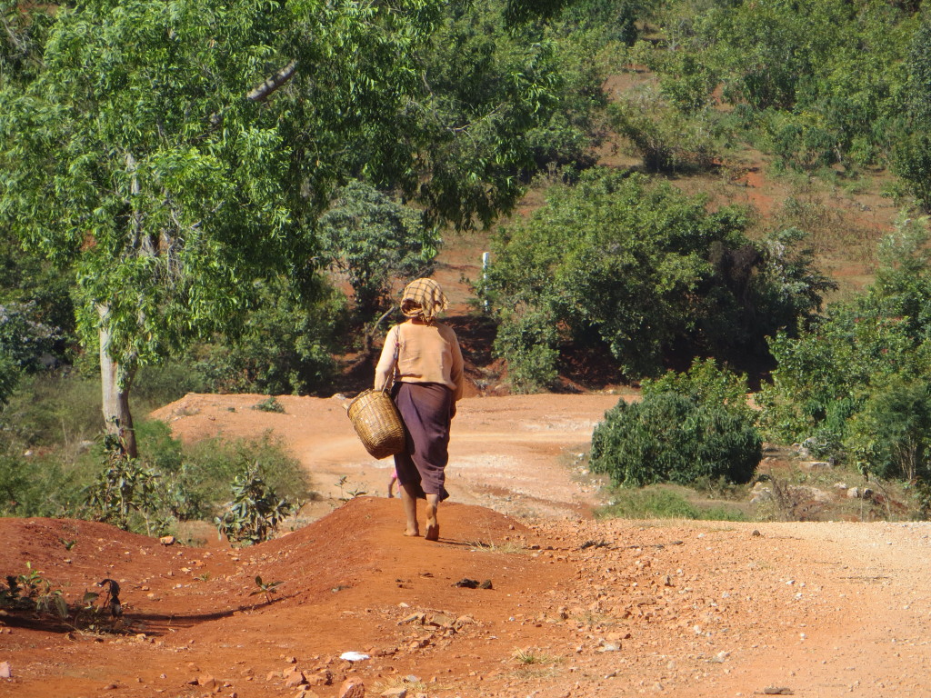A very typical stretch of road - dirt and gravel, with local people walking along