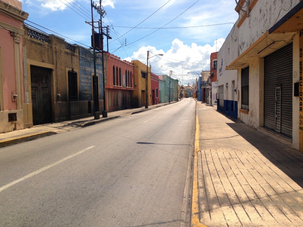 The nearly deserted streets of Mérida heading directly into the main square at mid-day. With the sun directly overhead there were no shadows, no place to hide, and not a lot of activity.